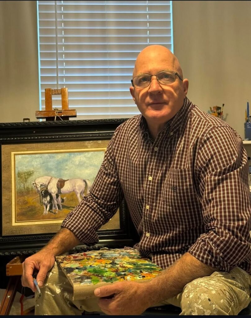 Retrato de um homem ao lado de sua obra de arte que retrata um cavalo branco.