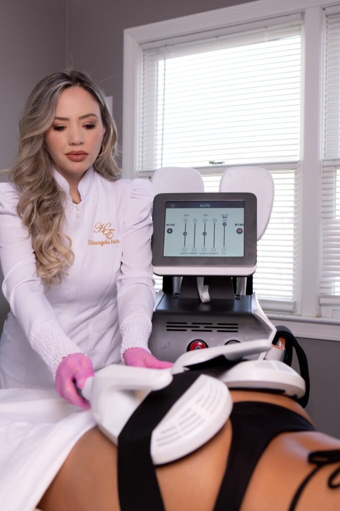 A especialista Elisangela Hein operando equipamento de alta tecnologia para contorno corporal em uma paciente na clínica Hein Esthetics.