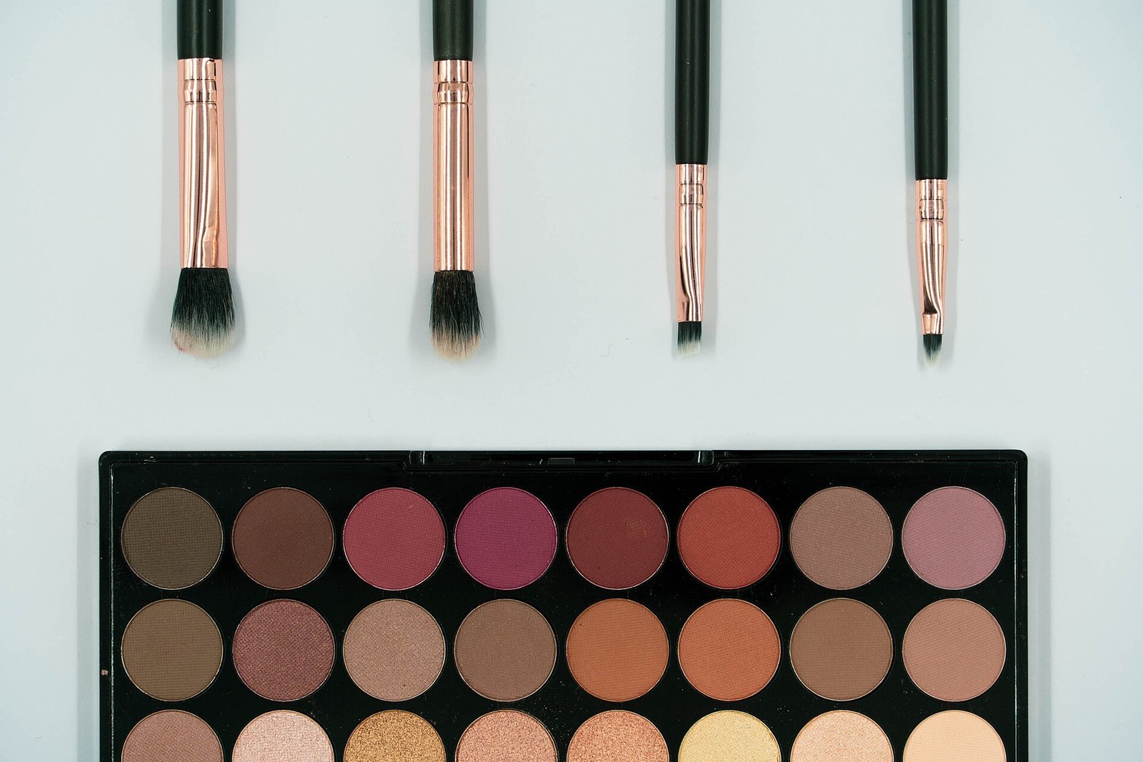 Pincéis de maquiagem e paleta de sombras sobre fundo claro