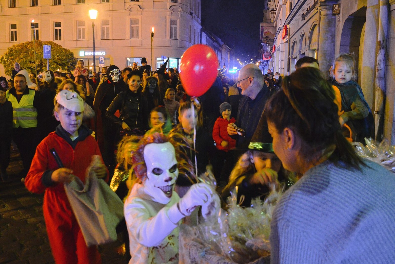 Crianças fantasiadas pedindo doces em rua movimentada à noite