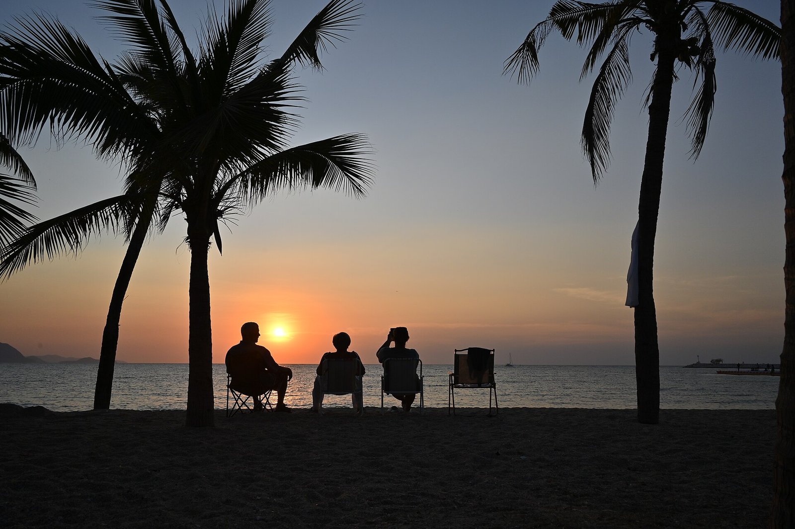 Amigos sentados na praia observando o pôr do sol